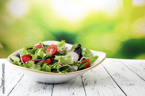 Cuadros en Lienzo bowl of salad with vegetables and greens, with tomato, cucumber and onions