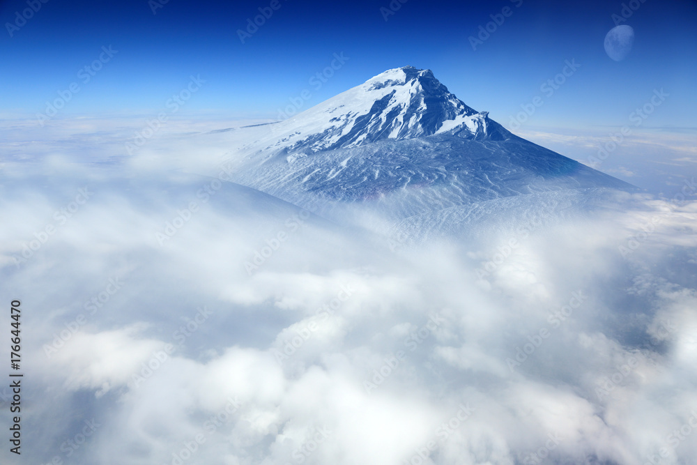 Szczyt górski pokryty śniegiem w chmurach. - obrazy, fototapety, plakaty 