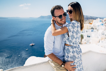 Happy couple hugging and laughing together with a view of Santorini