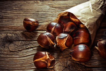 chestnuts in paper bag on old wooden background