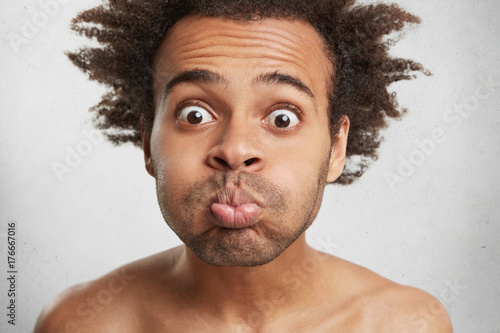 Close Up Of Mixed Race Male With Funky Hair Blows Cheeks