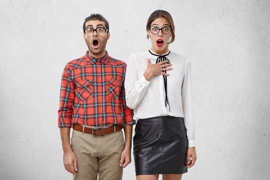Horizontal portrait of shocked clever female and male with widely opened mouth, don`t believe their eyes, realize that they have deadline for preparation on exam, not know from what to begin