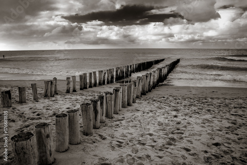 Plakat Piksele na plaży, do morza Krótkie pikiety w mokrym piasku na plaży, otoczone wodą z przypływu