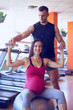 © ArtFamily - Smiling pregnant woman exercising in gym with personal trainer