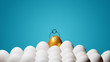 Concept of individuality, exclusivity, better choice, winning and ambition. A smiling golden egg with funny drawn face and with a crown among white eggs on blue background.