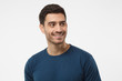 © Damir Khabirov - Close up portrait of smiling handsome male in blue t-shirt looking right, isolated on gray background