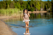 Beautiful Girl In A Dress Walking Along The Shore Of The Lake And Having Fun.