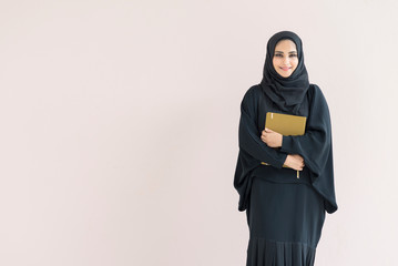  Arabian woman standing and holding a book.