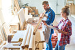 Portrait of two carpenters evaluating quality  of wood in workshop studio, choosing best materials