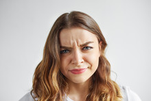 Negative Human Emotions And Feelings. Picture Of Displeased Grumpy Young Woman Posing At Blank Studio Wall, Frowning Eyebrows, Her Look And Grimace Expressing Anger, Annoyance And Irritation
