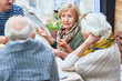 © Seventyfour - Portrait of senior people enjoying dinner together, focus on lady telling stories to friends gesturing actively