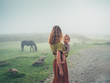 © LoloStock - Mother with baby in sling looking at horse in fog