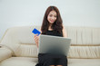 © nikomsolftwaer - Young woman holding credit card and using laptop computer. Online shopping concept