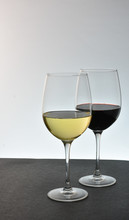 Two Staggered Glasses Of Wine With White Wine In Front Of Red