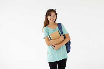 Wall Mural - Isolated shot of cute casually dressed female A-student of mixed race appearance carrying backpack on her shoulder and holding books, going to classroom, looking at camera with happy confident smile