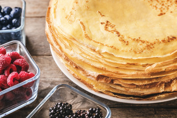 Wall Mural - Stack of delicious thin pancakes on plate served with berries, closeup