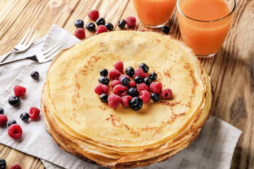 Canvas Print - Plate with delicious thin pancakes and berries on wooden background