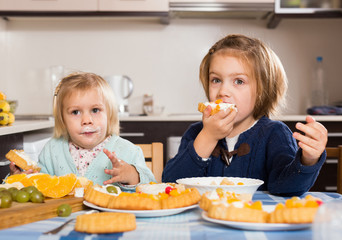 Wall Mural - Two little girls enjoying pastry with cream