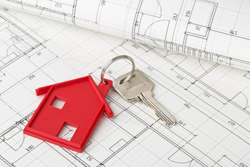 House door key with red house key chain pendant on building plans