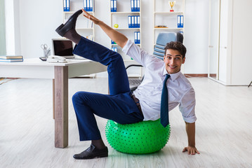 Young businessman doing sports stretching at workplace