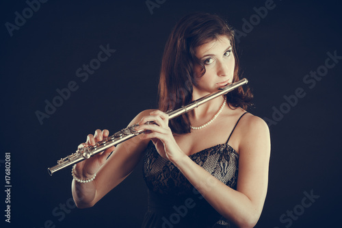 Plakat Kobieta bawić się poprzecznego flet na czerni.