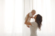© demphoto - Mom holds a baby in the arms window background