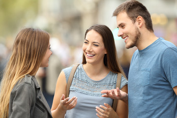 Wall Mural - Three smiling friends talking standing on the street