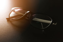 Closeup Eyeglasses On Black Table With Soft-focus And Over Sunlight In The Background
