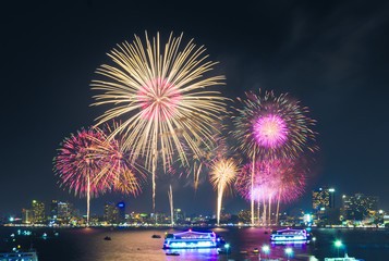 Fireworks over cityscape by the beach and sea surrounding with hotels, restaurant, and service boats and cruises for celebrating New Year eve and special occasion on holidays