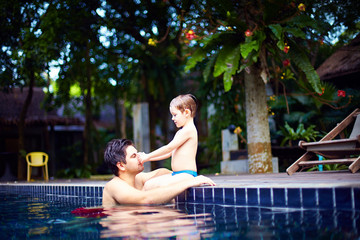  father and son enjoy relaxing in the pool at quiet getaway