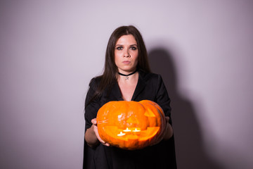 Jack o Lantern Halloween pumpkin grinning in the most evil fashion in woman's hands.