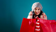 © Tierney - Happy young woman holding shopping bags on a solid background