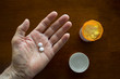 © David Smart/Stocksy - First person POV of a hand holding two round white tablets.