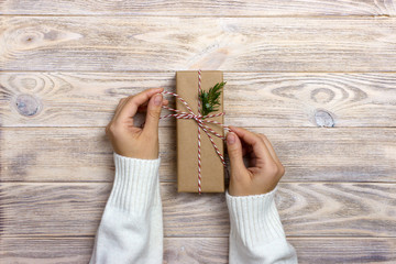 Woman holding a christmas gift in hand on wooden background