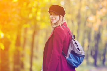 Sticker - woman in red coat and backpack have a rest in autum park