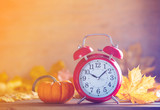 Fototapeta Tematy - Vintage alarm clock and maple tree leaves with pumpkins
