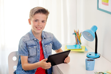 Poster - smiling boy with tablet pc sitting at home desk