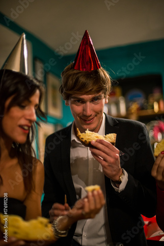 Zdjęcie XXL Młody dorosły człowiek obchodzi Boże Narodzenie lub Sylwestra jedzenie tradycyjne włoskie panettone w przytulnym mieszkaniu kryty