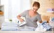 Happy woman housewife ironing clothes   in laundry at home.