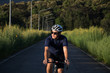 © immstudio - A young man riding a bicycle on a road through a green meadow during sunrise.