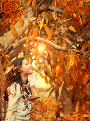 Plakat dziewczyna wśród drzew z suchymi liśćmi jesienią