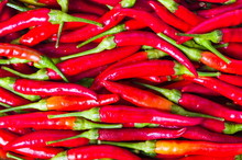 Thin Red Peppers On A Pile Background