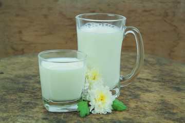 A bottle of milk and glass of milk on a wooden table on a  background