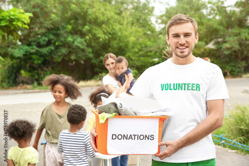Fotografía Young male volunteer holding box of donations outdoors