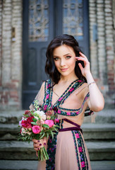 Wall Mural - Woman in beige dress with red bouquet in her arm stands on stone footsteps