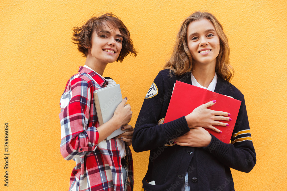 Portrait of two young teenage girls with books standing Stock Photo ...