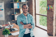 Portrait Of Successful Black Guy, Looking At The Camera, Standing With Crossed Arms At His Work Place In The Office, In Casual Smart, Smiling