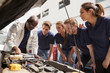 © Monkey Business - Mechanic instructing trainees around a car engine, low angle