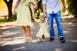 Amazing parents walk with their little daughter in yellow dress in the park