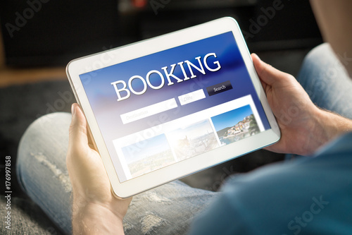 Zdjęcie XXL Aplikacja do rezerwacji lub strona internetowa na ekranie tabletu. Mężczyzna szuka hotel i loty na wakacje i wakacje z aplikacji podróży. Osoba posiadająca inteligentne urządzenie w ręku.